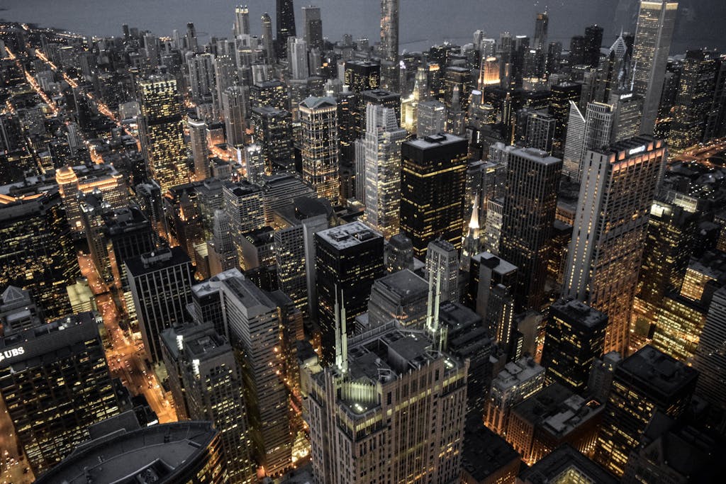 Explore the vibrant skyline of Chicago with its illuminated skyscrapers and bustling urban life captured at dusk.