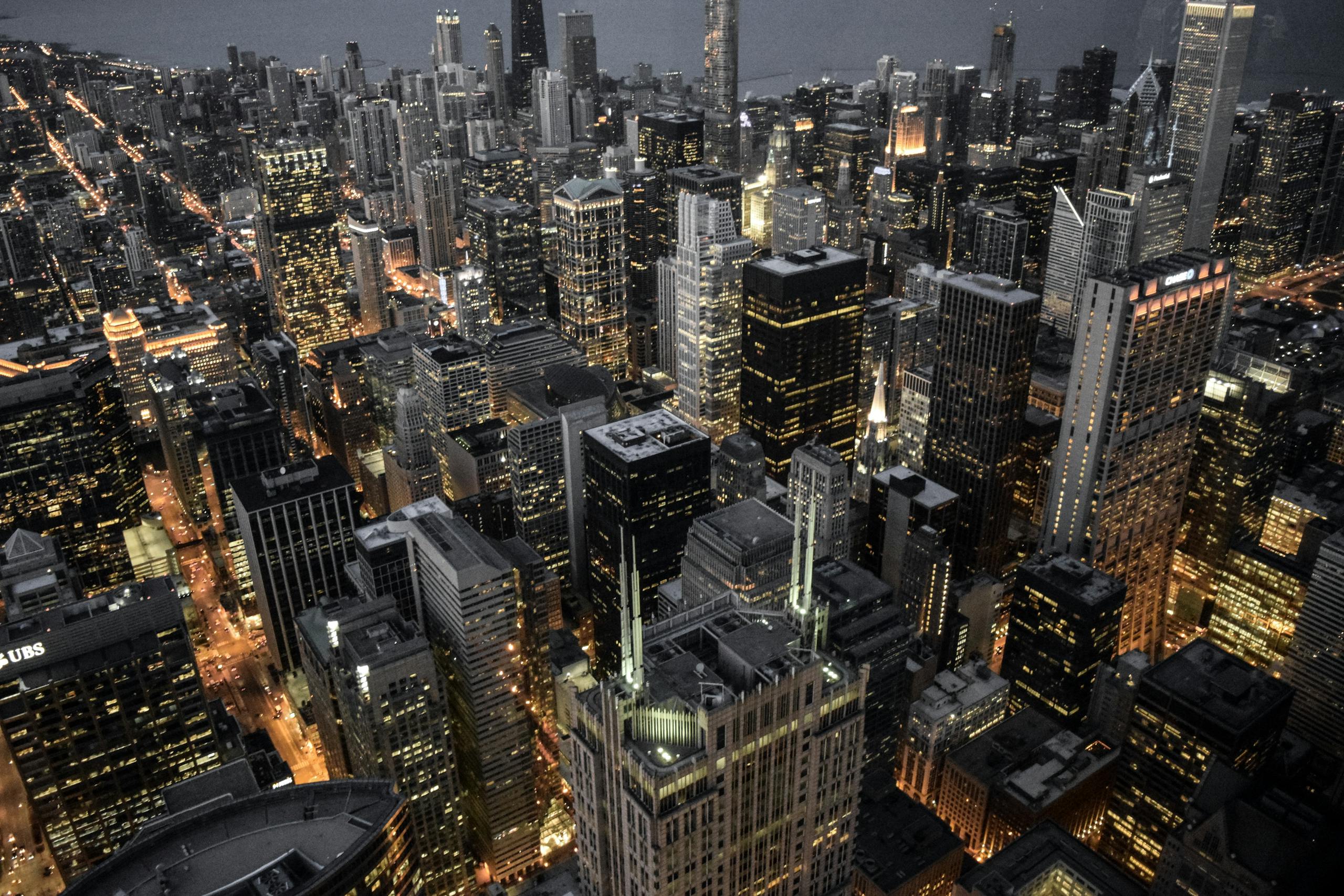 Explore the vibrant skyline of Chicago with its illuminated skyscrapers and bustling urban life captured at dusk.